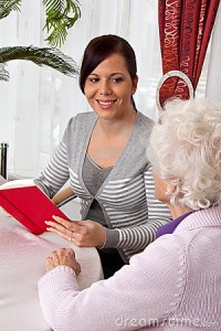 A young woman reads to seniors from a book