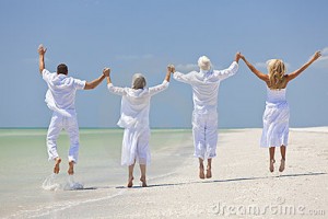 Seniors and family having fun and jumping in celebration on a tropical beach